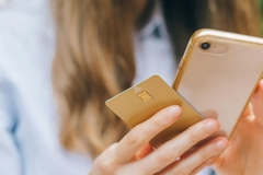 Image A woman holding her phone and her credit card.