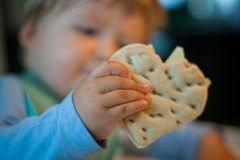 Image A poor toddler eats heart shaped bread.