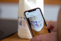 Image A person taking a picture of the labeling on a milk container