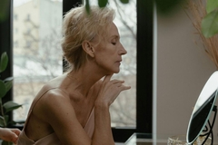 Image older woman looks into mirror on dressing table