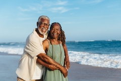 Image Old couple laughing by beach