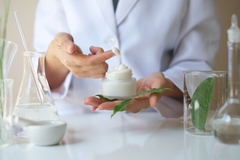 Image scientists holds moisturizer with finger coated in it