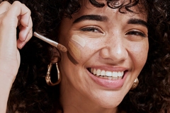 Image smiling woman applies foundation shades on cheeks
