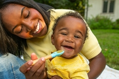 Image a woman feeding a baby with a spoon.