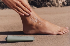 applying cream on foot with tube next to it
