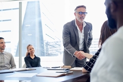 Image Two business persons shake hands in a large office.