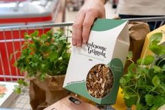 Image Person placing paper-based granola packaging in shopping chart.