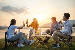 Image two young men and two young women drinking beer on the beach.