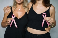 Image Women holding pink breast cancer ribbons up to their chests.