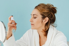 Image A woman using a spray on her face.