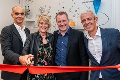 Image three men and a woman cutting a ribbon.