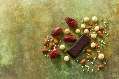 Image A chocolate bar with dates and nuts by it.