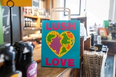 Image A Lush bag with the world in the shape of a heart on it.