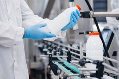 Image Lab worker looking at plastic bottle wearing gloves.