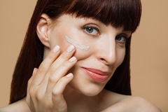 Image smiling woman applies cream to cheek
