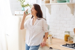 A woman looking relaxed as she's drinking a glass of water with mineral salts.