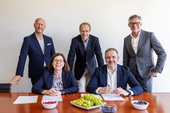 Image four men and one woman in suit with fruits on a table.