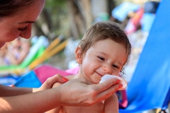 Image woman wipes face of smiling baby