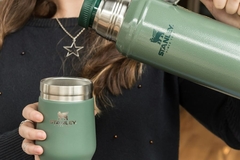 Hands pouring from a Stanley flask into a cup.