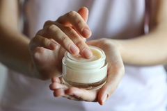 Image Fingers dipping into a pot of moisturizer.
