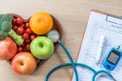 Image A diabetes test with a stethescope and a heart-shaped bowl of fruit on a table.