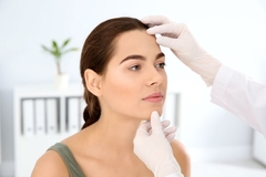 Image A woman getting her faced touched by a doctor.