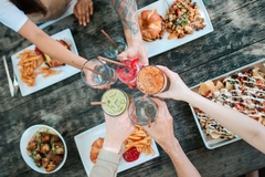 hands holding plant based drinks with vegan food on the table.