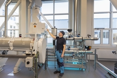 Image a man working in a food factory with milling equipment.