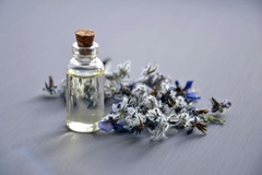 Image A bottle of liquid with flowers next to it.