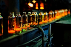 A row of glass bottles on a conveyor belt.