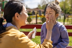 A mother applying sunscreen on her kid.