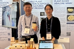 a male and a female scientist holding a sample of sorghum protein at an event.