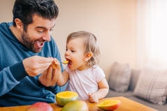 A father feeding his baby fruit puree without sugar.