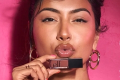 Image A woman holing an ELF lipstick to her mouth and puckering.