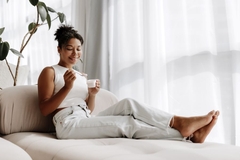 Image Woman, relaxing and eating a yogurt for good gut health.