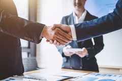 Two business people shaking hands on an acquisition deal.