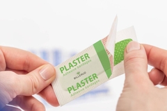 A person taking out a plaster adhesive bondage from paper packaging.