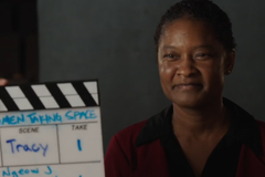 A woman sitting in front of a start slate for film.