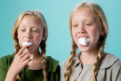 Two girls in pigtails and mouth stuffed with marshmallows