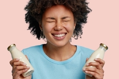 Image a young girl holding two bottles of plant based milk