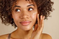 woman with few dots of moisturizer on her cheek