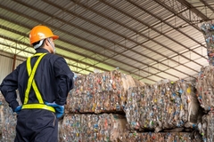 Image A person standing in front of a large pile of plastics in a factory