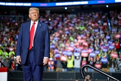 Image Trump stands on stage with supporters in background
