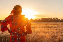 Image Zimbabwean woman with hands on hips as she looks onto a field during sunset