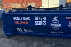 A blue recycling bin is placed in the outdoor environment.