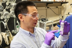 Image A Chinese man in a lab coat holding a bottle