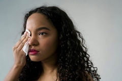 Image A woman wiping off her makeup with a wet wipe.