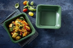 A green container with food in it.
