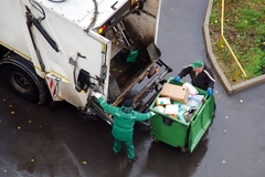 Image Two people loading garbage into a garbage truck
