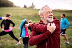 Image A man stretching after exercise with a group on a hill.